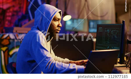 Hacker using VPN and darknet as anonymity tools to mask his online identity while committing data breaches. Cybercriminal in underground bunker masking his location hacking into servers 112977185