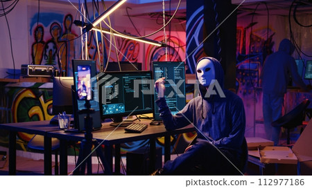 Dissident social justice crusaders doing online activism, wearing anonymous masks and filming video in underground bunker, blackmailing government after stealing secret military documents 112977186