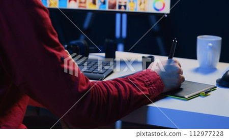 Photographer using graphic tablet to perform editing operations to correct images in creative agency. Photo editor using stylus on touchscreen device to make adjustments to photographs, close up Photographer using graphic tablet to perform editing operations to correct images in creative agency. Photo editor using stylus on touchscreen device to make adjustments to photographs, close up 112977228