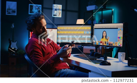 Photographer taking break from using photo editing software on PC display, texting friends to relax. Freelancer stops using photographs retouching program to spend time on mobile phone Photographer taking break from using photo editing software on PC display, texting friends to relax. Freelancer stops using photographs retouching program to spend time on mobile phone 112977231