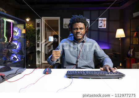 Excited gamer feeling happy after winning PC game during live stream with viewers. Delighted player bragging after being victorious in videogame while broadcasting gameplay for audience 112977275