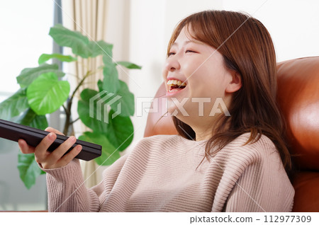女人坐在沙發上,看電視 女人坐在沙發上,看電視 112977309