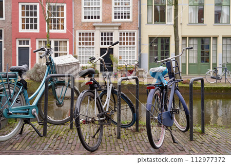 Picturesque Netherlands. Bicycles parked alongside a channel on beautiful old buildings background. 112977372