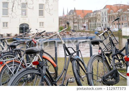 Delft, Netherlands. Bicycles parked alongside a channel on beautiful old buildings background. 112977373