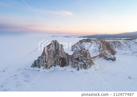 Aerial shot of a Shamanka rock on Olkhon island at sunset. Winter landscape. Popular touristic destination. Natural landmark. Panoramic view 112977487