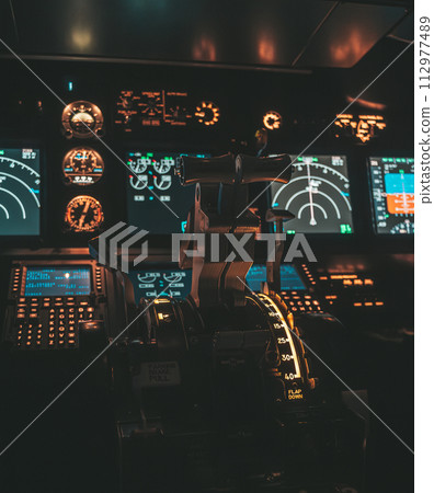 Cockpit view of an airplane during a night-time flight with illuminated instrument panels Cockpit view of an airplane during a night-time flight with illuminated instrument panels 112977489