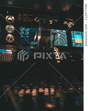 Cockpit view of an airplane during a night-time flight with illuminated instrument panels Cockpit view of an airplane during a night-time flight with illuminated instrument panels 112977490
