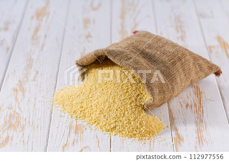 Raw couscous in sack on a light table, selective focus. Raw couscous in sack on a light table, selective focus. 112977556