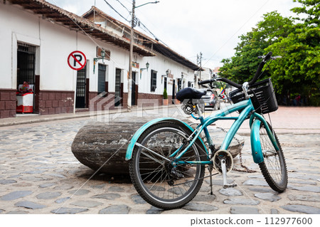 Vintage blue bike parked at the beautiful streets around the central square of the Heritage Town of Guaduas located in the Department of Cundinamarca in Colombia. Vintage blue bike parked at the beautiful streets around the central square of the Heritage Town of Guaduas located in the Department of Cundinamarca in Colombia. 112977600