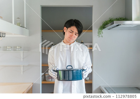 廚房裡拿著鍋子的憂心忡忡的男人,不擅長做飯的丈夫,家庭主婦,做飯的男孩 廚房裡拿著鍋子的憂心忡忡的男人,不擅長做飯的丈夫,家庭主婦,做飯的男孩 112978805