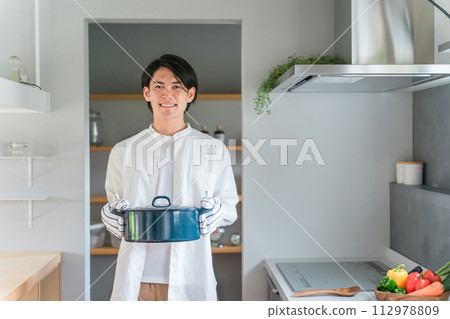 廚房裡拿著鍋子的年輕人，喜歡做菜的丈夫，家庭主婦，做菜的男孩 112978809