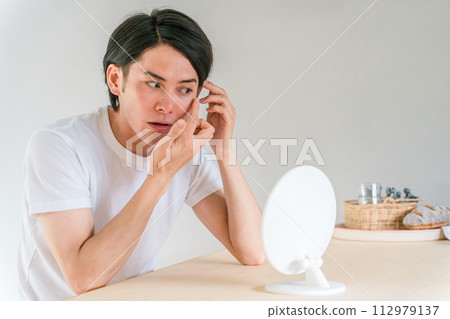 A man who looks at wrinkles around the corners of his eyes and wears contact lenses 112979137