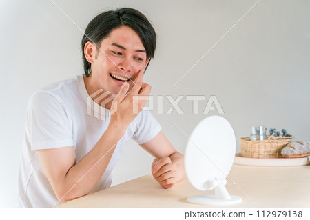 A man who looks at wrinkles around the corners of his eyes and wears contact lenses A man who looks at wrinkles around the corners of his eyes and wears contact lenses 112979138