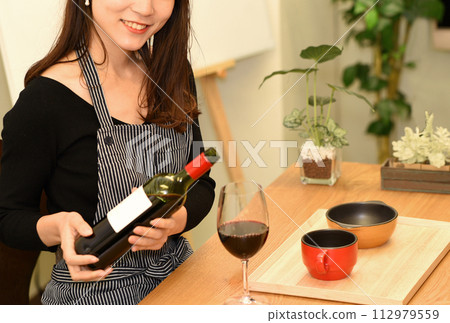年輕的亞洲女性在室內倒紅酒 112979559