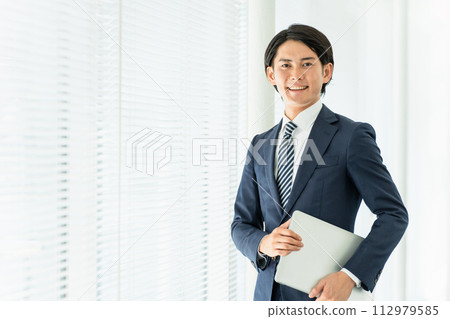 一位穿著西裝、在辦公室配有筆記型電腦的男性商人（專業人士、稅務會計師、律師、司法書士） 112979585