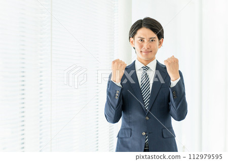 Young Asian male businessman fist pumping in the office (motivation, success, support, achievement) 112979595