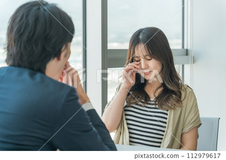 女性受害者和男性律師/顧問在律師事務所/諮詢櫃檯諮詢（詐騙受害者、個人破產、哭泣/擔心） 112979617