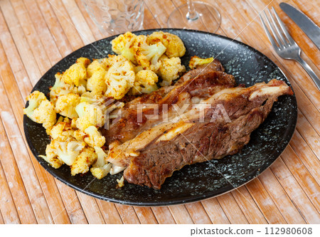 Fried lamb served with cauliflower on platter 112980608