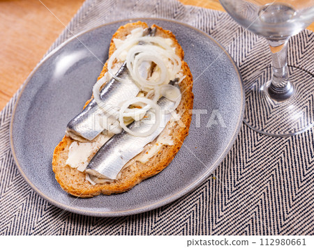 On plate - homemade light snack toast, sandwiches with herring, butter, decorated with onion On plate - homemade light snack toast, sandwiches with herring, butter, decorated with onion 112980661