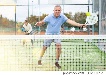 Emotional mature man playing paddle tennis outdoors 112980734