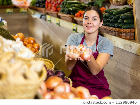 Young woman selling onions in shop 112980940