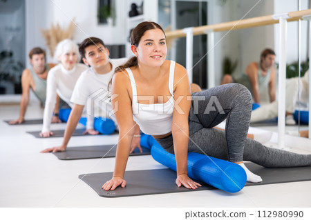Young woman practicing pilates with roller in gym room 112980990