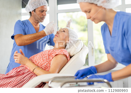 Woman applying rejuvenating treatments by male doctor. 112980993