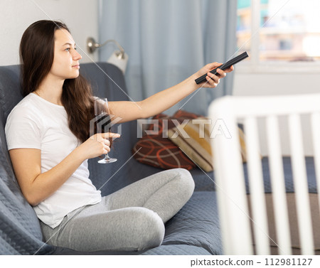 Woman drinking wine watching TV at home 112981127