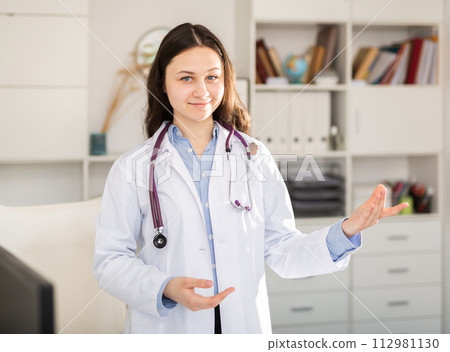 Positive young female trainee doctor stands in a welllit resident's office 112981130