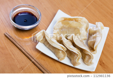 Boiled Yaki Gyoza served in plate with special sauce and chopsticks Boiled Yaki Gyoza served in plate with special sauce and chopsticks 112981136