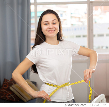 Portrait of woman taking measurements of body 112981193