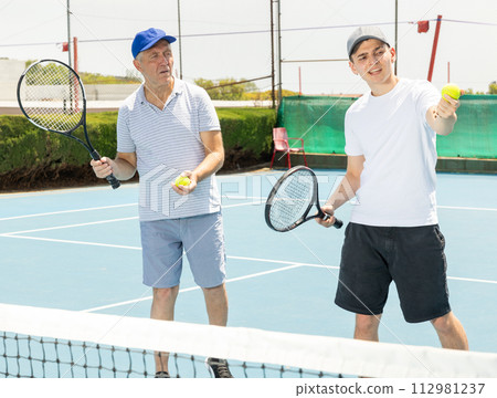 Man is taught tennis by young guy coach. 112981237