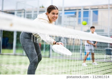 Young sporty woman playing paddle tennis outdoors 112981314