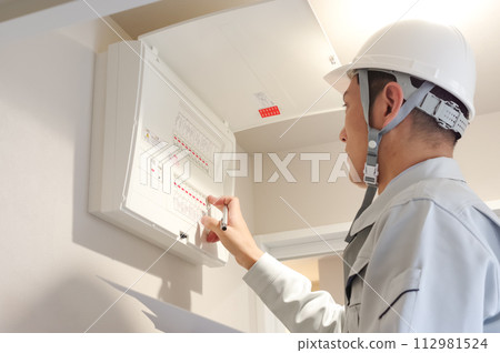 一名穿著工作服的男子正在檢查交換機 112981524