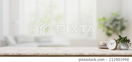 A luxurious white marble tabletop against the backdrop of a blurred modern white living room. 112981998