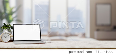 A luxurious marble table is adorned with a white-screen laptop computer in a modern living room. 112981999