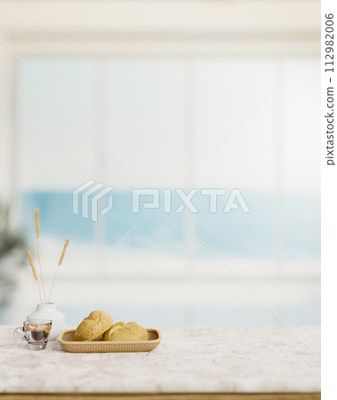 A bread basket and a coffee cup on a white marble table in a modern white beach house living room. 112982006
