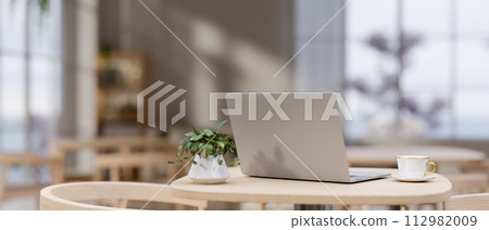 A back view image of a laptop computer on a wooden table in a modern cozy neutral coffee shop. A back view image of a laptop computer on a wooden table in a modern cozy neutral coffee shop. 112982009