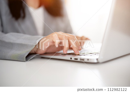 A cropped image of a businesswoman working or browsing on the laptop, working in a modern office. 112982122