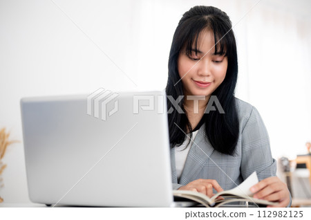 A beautiful young Asian businesswoman or secretary working at her desk in a modern bright office. 112982125
