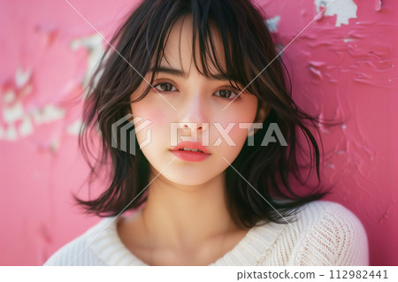 Portrait of a young Japanese woman against a pink background 112982441