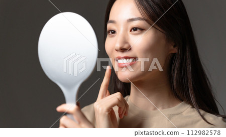 A woman watching a hand mirror 112982578
