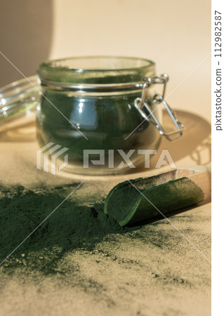 Organic blue-green algae spirulina powder food in glass jar with wooden spoon. Health benefits of spirulina chlorella. Vitamins and minerals to diet. Detox dietary supplement Seaweed superfood Organic blue-green algae spirulina powder food in glass jar with wooden spoon. Health benefits of spirulina chlorella. Vitamins and minerals to diet. Detox dietary supplement Seaweed superfood 112982587