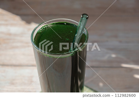 Natural organic green spirulina algae powder drink on neutral beige background. Chlorella seaweed vegan superfood cocktails smoothie supplement source and detox drinking. Innovative ingredient 112982600