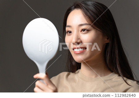 A woman watching a hand mirror 112982640