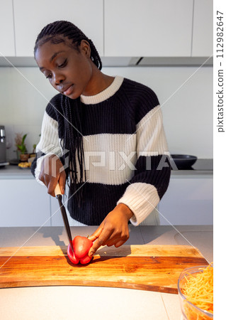 Focused Woman Preparing Food in a Modern Kitchen Focused Woman Preparing Food in a Modern Kitchen 112982647