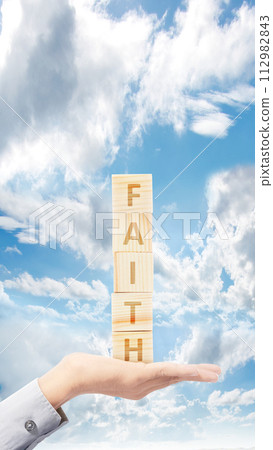 A human hand holding a stack of a cube with the text of Faith A human hand holding a stack of a cube with the text of Faith 112982843