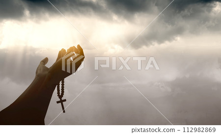 Christian man praying with raised hands and rosary beads 112982869
