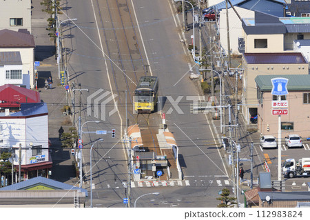 [Logo and other retouching completed] Hakodate City Tram 2 entering Yachigashira stop and departing (yellow train) 112983824