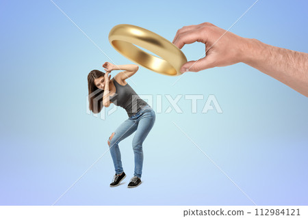 Woman ducking under giant golden coin ring 112984121